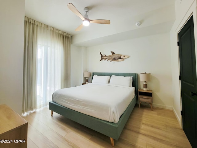 bedroom featuring light wood-type flooring, ceiling fan, and multiple windows