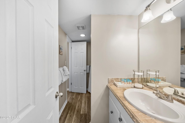 ensuite bathroom featuring visible vents, ensuite bathroom, wood finished floors, baseboards, and vanity