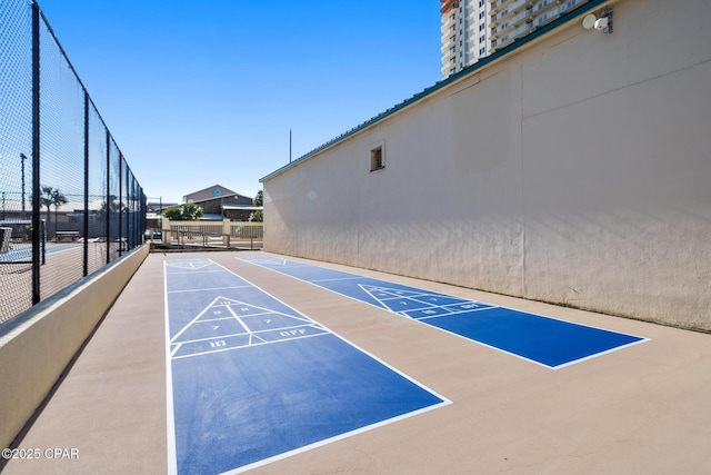 view of property's community with shuffleboard and fence