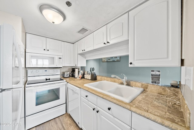 kitchen featuring a sink, white appliances, and white cabinetry