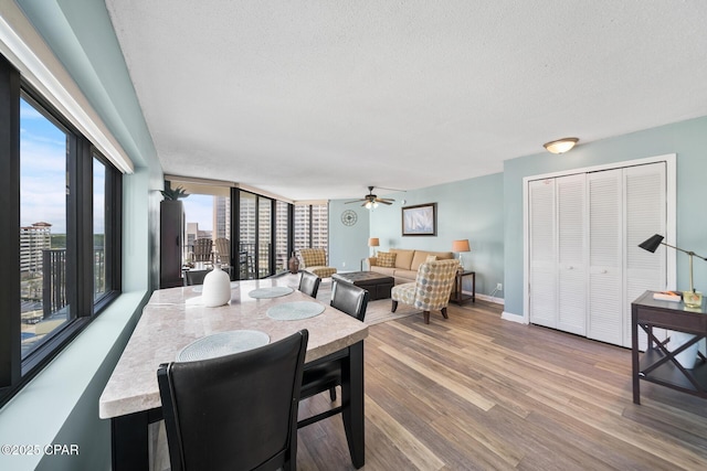 dining room with ceiling fan, wood finished floors, baseboards, and a textured ceiling