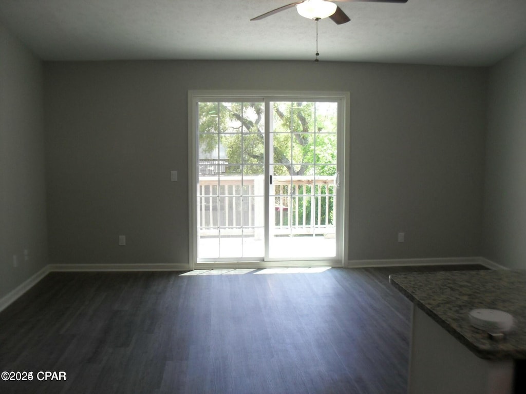 interior space with a ceiling fan, dark wood-type flooring, and baseboards