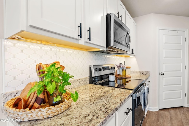 kitchen featuring wood finished floors, appliances with stainless steel finishes, white cabinetry, and light stone countertops