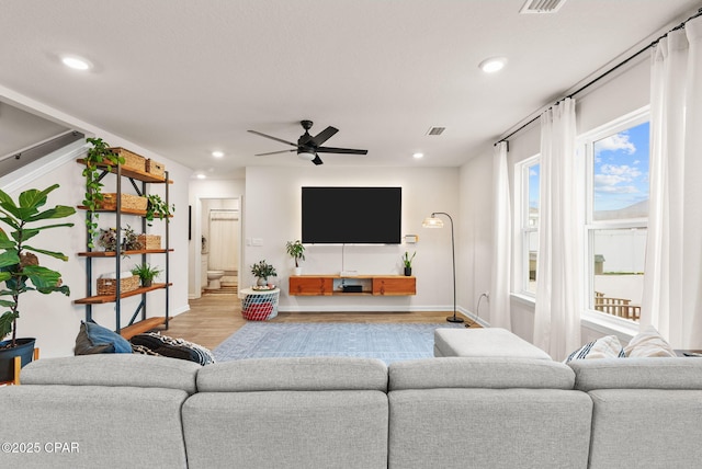 living area featuring visible vents, baseboards, ceiling fan, recessed lighting, and wood finished floors