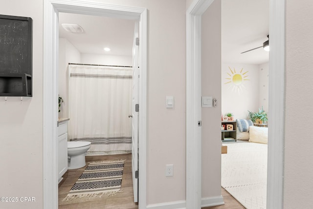 full bathroom with toilet, curtained shower, wood finished floors, baseboards, and ceiling fan