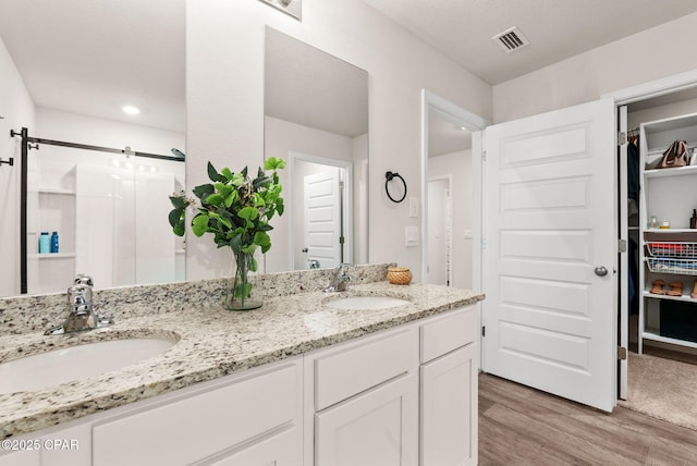 bathroom with double vanity, visible vents, wood finished floors, and a sink