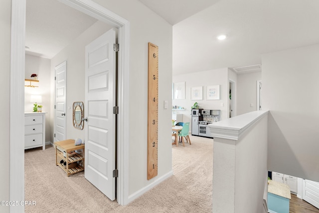 corridor featuring recessed lighting, light colored carpet, baseboards, and an upstairs landing