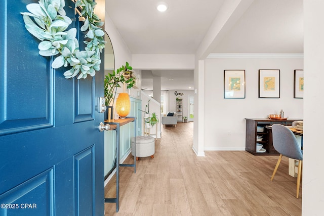 foyer entrance featuring crown molding, stairway, wood finished floors, and baseboards