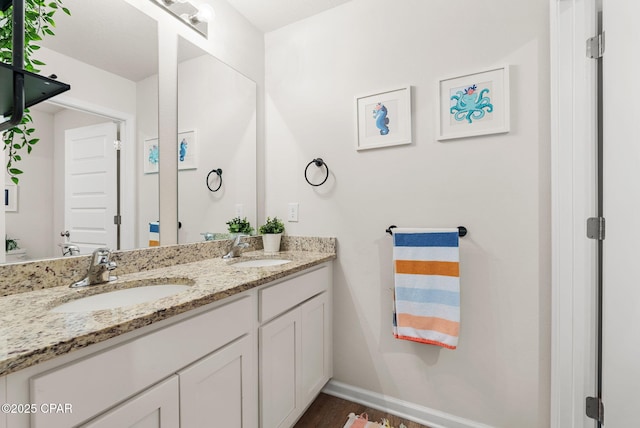 full bath with a sink, baseboards, and double vanity