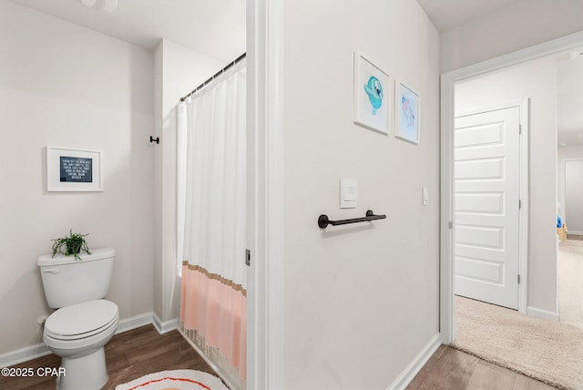 full bath featuring a shower with curtain, baseboards, toilet, and wood finished floors