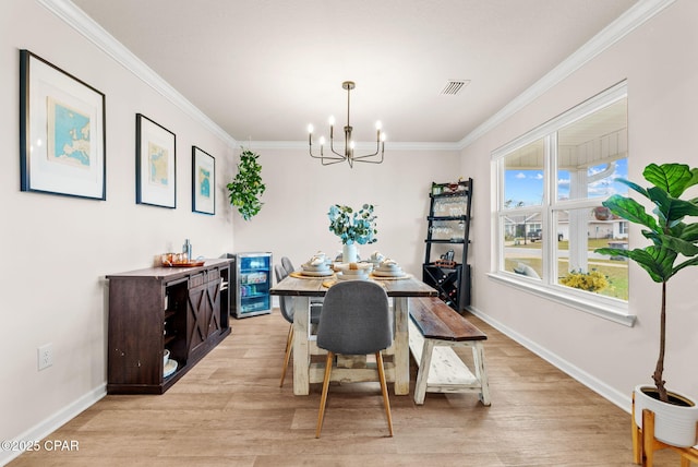 dining room featuring visible vents, ornamental molding, an inviting chandelier, light wood finished floors, and baseboards