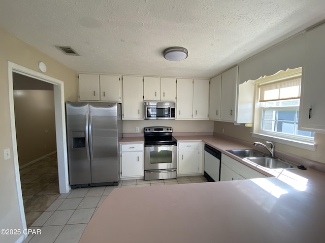 kitchen with light tile patterned flooring, white cabinetry, stainless steel appliances, and a sink