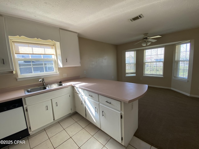 kitchen with visible vents, a peninsula, a sink, light countertops, and dishwasher