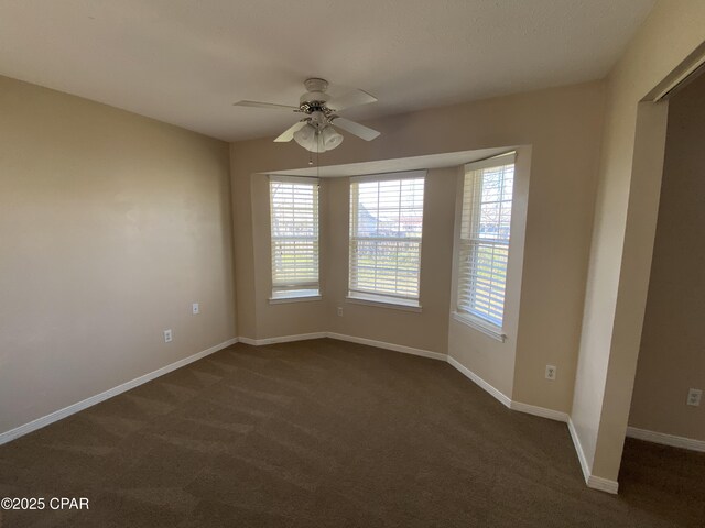 unfurnished room featuring dark carpet, a ceiling fan, and baseboards