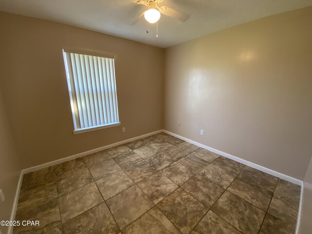 empty room with a ceiling fan and baseboards