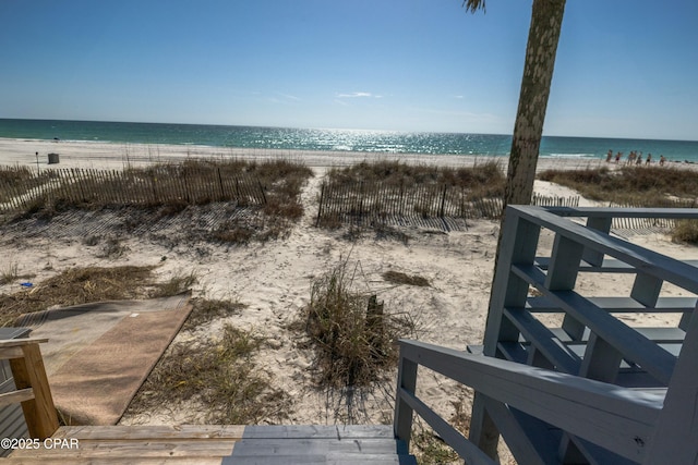 property view of water with fence and a beach view