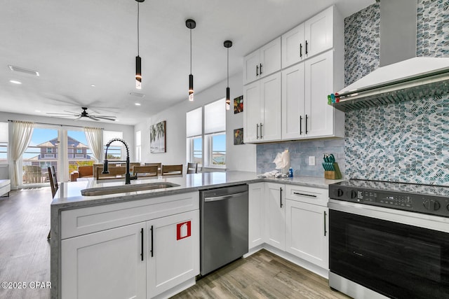 kitchen featuring wall chimney range hood, electric range oven, stainless steel dishwasher, white cabinets, and a sink