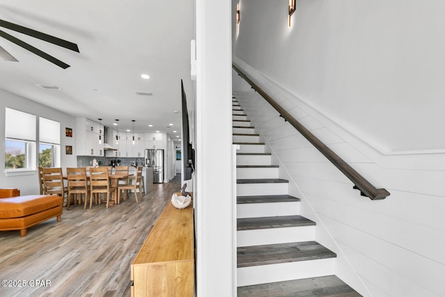 stairs with a ceiling fan, recessed lighting, wood finished floors, and visible vents