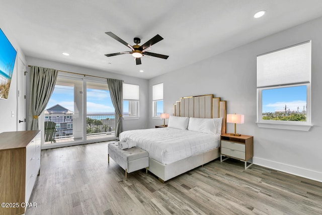 bedroom with access to outside, multiple windows, and wood finished floors
