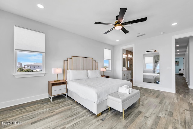 bedroom featuring visible vents, multiple windows, baseboards, and wood finished floors