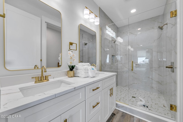 bathroom featuring vanity, recessed lighting, wood finished floors, and a marble finish shower