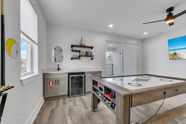 recreation room featuring a ceiling fan, wet bar, a sink, wine cooler, and light wood-style floors