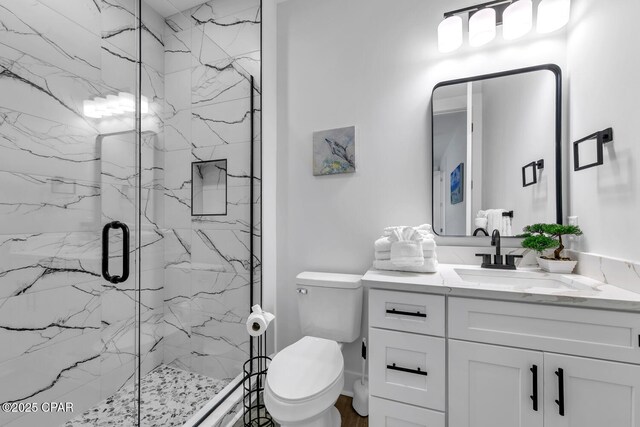 full bathroom featuring a marble finish shower, toilet, and vanity