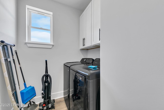 laundry area featuring washer and clothes dryer, cabinet space, baseboards, and wood finished floors