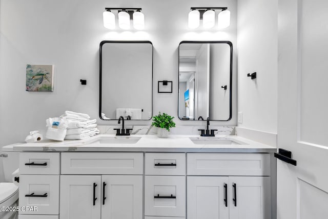 full bathroom with double vanity, toilet, and a sink