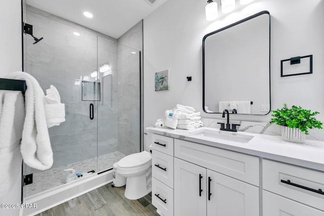 bathroom featuring vanity, wood finished floors, recessed lighting, a shower stall, and toilet