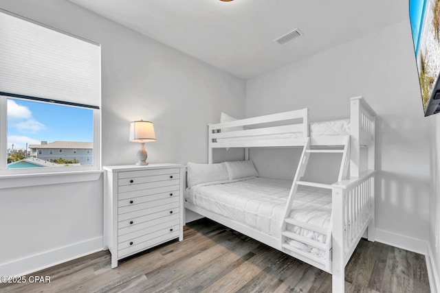 bedroom with visible vents, baseboards, and wood finished floors