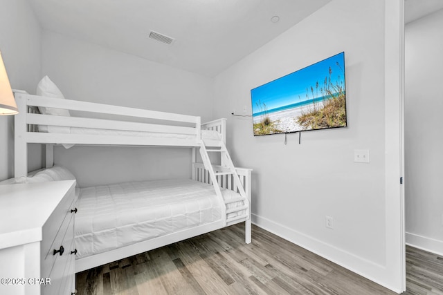 bedroom with wood finished floors, visible vents, and baseboards