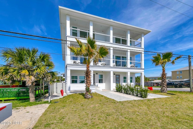 view of front of house featuring a balcony, a front yard, and fence