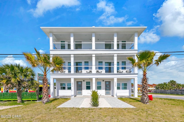 raised beach house featuring a front yard and a balcony