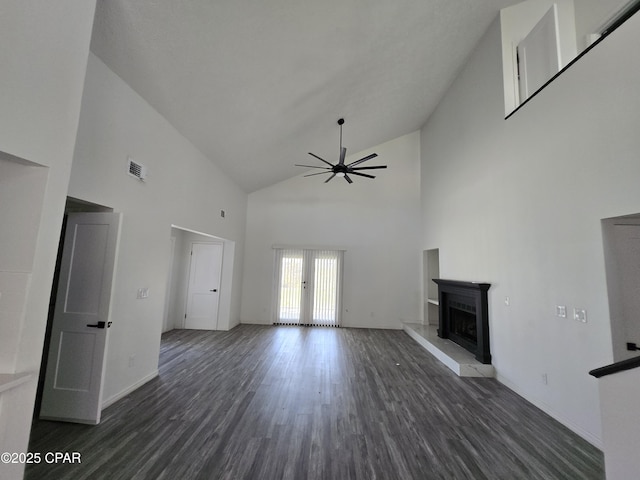 unfurnished living room with visible vents, a fireplace with raised hearth, wood finished floors, french doors, and ceiling fan