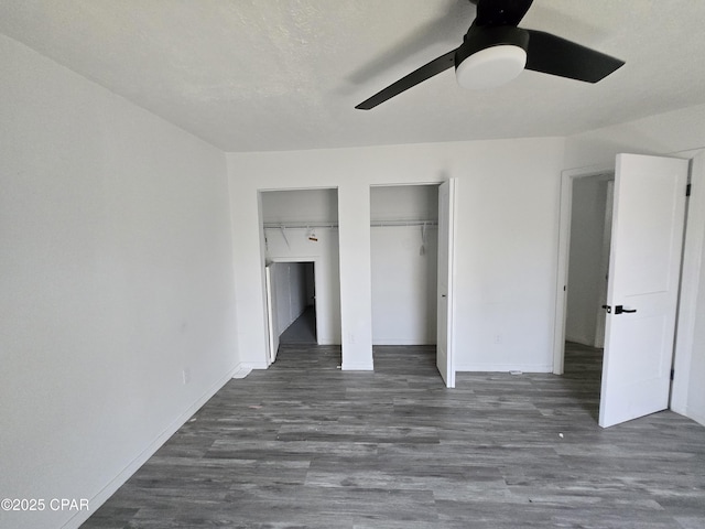 unfurnished bedroom with baseboards, a ceiling fan, multiple closets, and wood finished floors