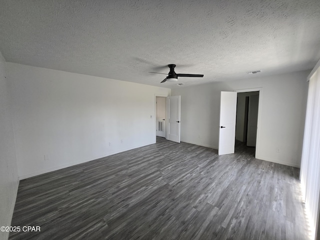 empty room with dark wood-type flooring, baseboards, visible vents, and a textured ceiling