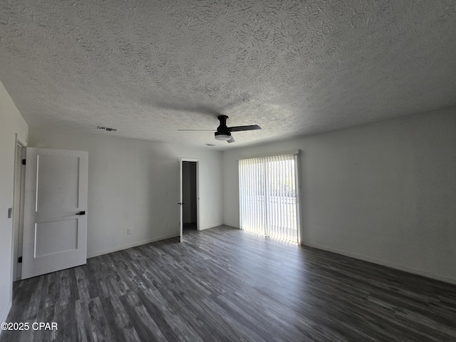 spare room with a textured ceiling, a ceiling fan, visible vents, dark wood-style flooring, and baseboards