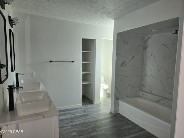 full bath featuring a sink, a textured ceiling, wood finished floors, and double vanity