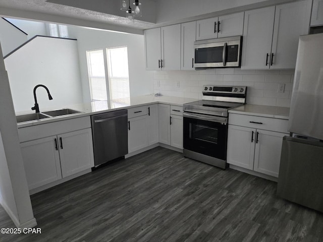 kitchen featuring tasteful backsplash, light countertops, appliances with stainless steel finishes, dark wood-style floors, and a sink