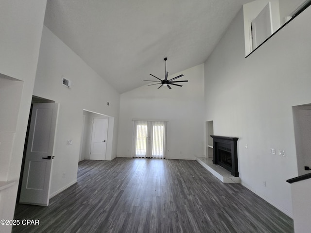 unfurnished living room featuring visible vents, a fireplace with raised hearth, a ceiling fan, wood finished floors, and high vaulted ceiling