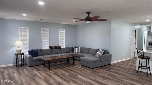 living area featuring dark wood-type flooring, baseboards, recessed lighting, a textured ceiling, and a ceiling fan