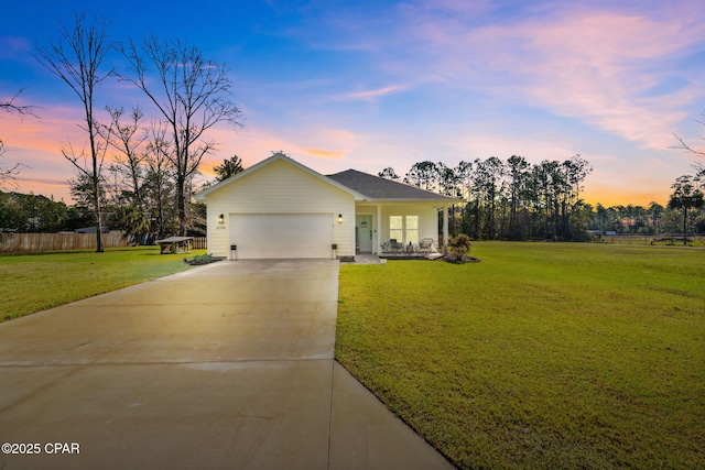 view of front of home with concrete driveway, an attached garage, a lawn, and fence