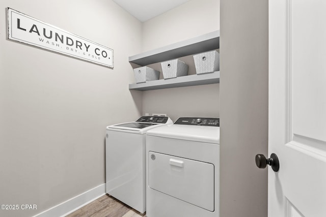 clothes washing area with laundry area, washer and dryer, light wood-style floors, and baseboards