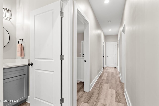 hall with recessed lighting, baseboards, and light wood finished floors