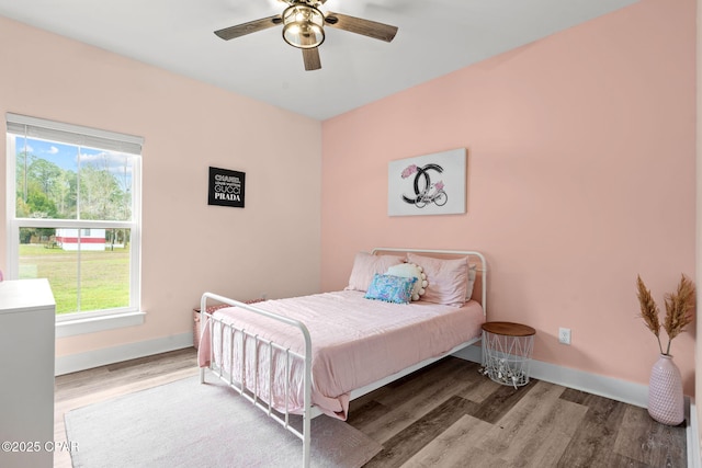 bedroom featuring ceiling fan, baseboards, and wood finished floors