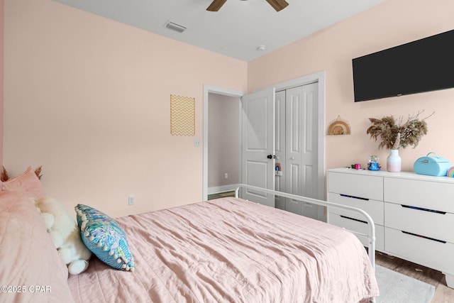 bedroom with visible vents, a closet, wood finished floors, and a ceiling fan