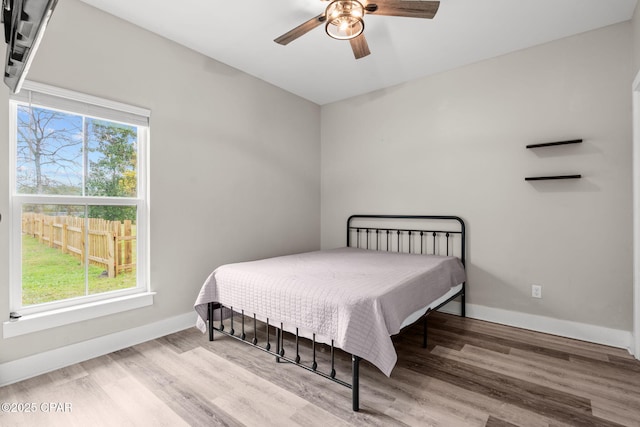 bedroom with multiple windows, wood finished floors, and baseboards