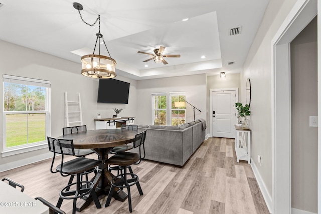 dining area with recessed lighting, visible vents, light wood-style flooring, and a tray ceiling