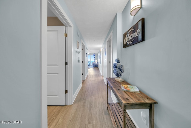 hallway featuring light wood-type flooring and baseboards